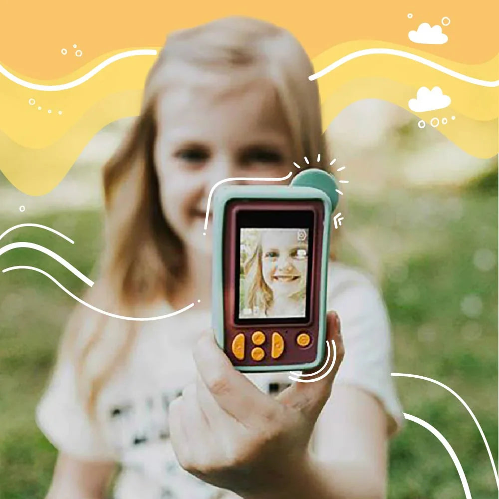 A young girl holds a teal and maroon digital camera, displaying her smiling reflection.