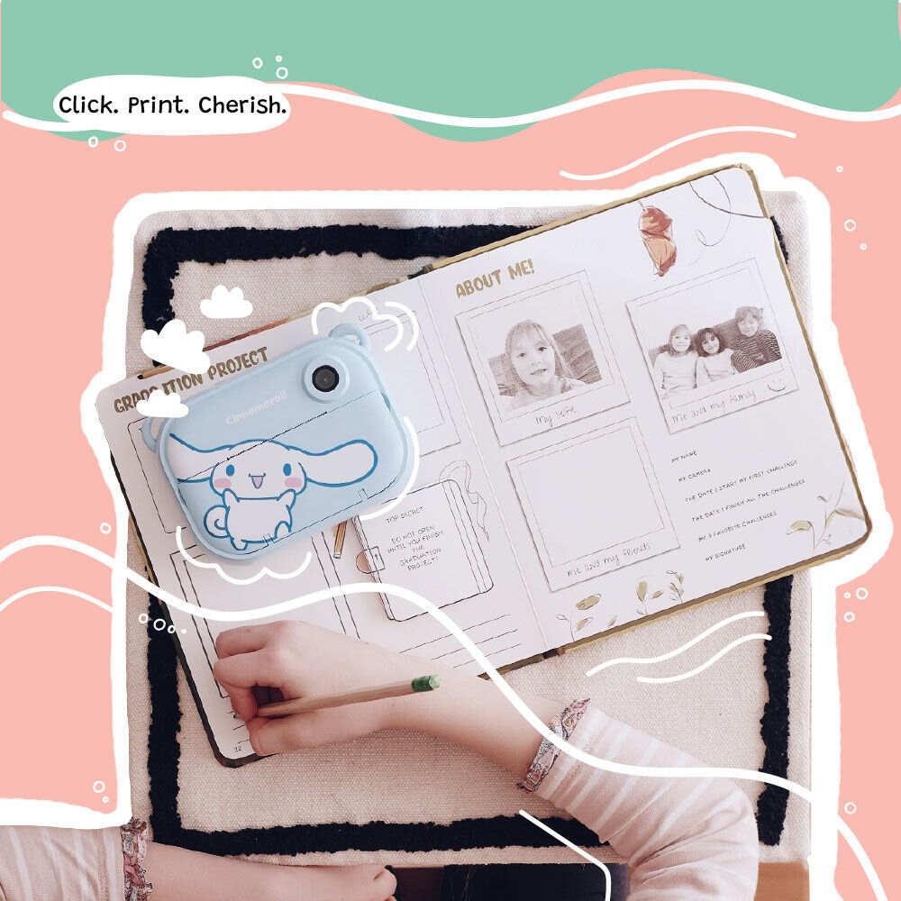 Lifestyle image of the kiimento Model P Cinnamoroll kids’ digital camera placed on an open scrapbook filled with printed photos. A child's hand is seen writing in the book, capturing a sweet moment of creativity and memory-keeping.