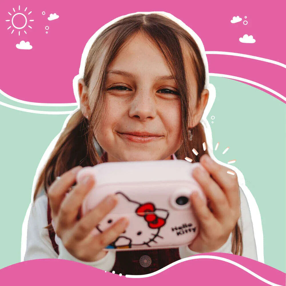 Smiling young girl holding the kiimento Hello Kitty Model P digital camera, showing joy and excitement. The front of the pastel pink camera with Hello Kitty’s face is clearly visible. The background features playful illustrations in pink, mint green, and white, evoking a cheerful, whimsical atmosphere.