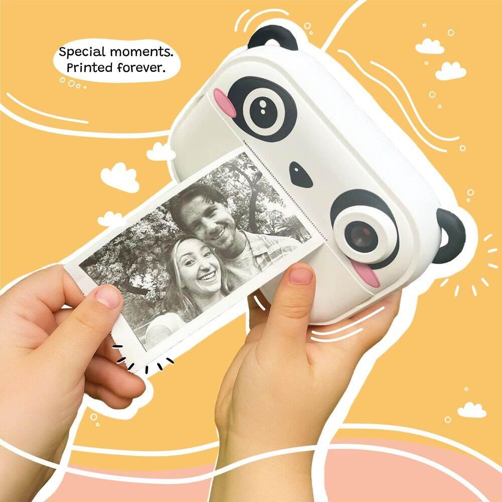 Hands holding kiimento Model P Panda camera printing a black and white photo instantly, with playful orange background.